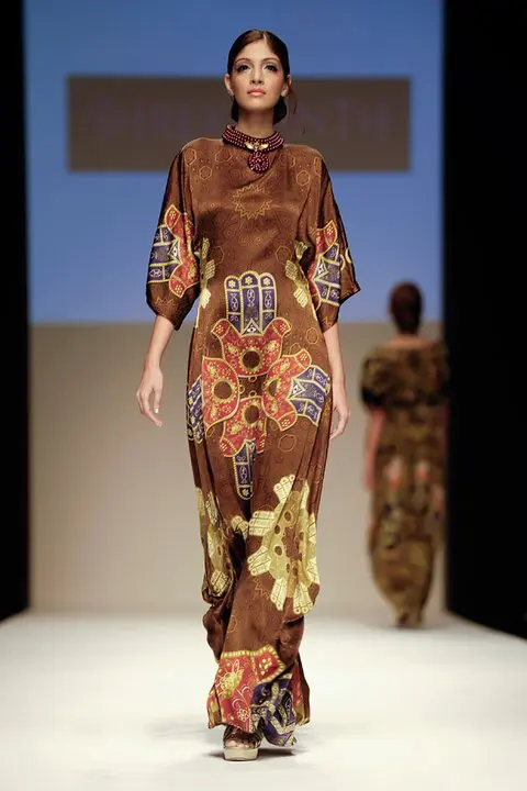 Arabian Nomads : Exclusive Arab Dress Collection at DFW, SS11 16 Kimono sleeve thobe-style dress with symmetric Hamsa motifs in yellow, red, and blue over a brown Islamic art canvas, with pearl and crystal embroidery on the round neckline.